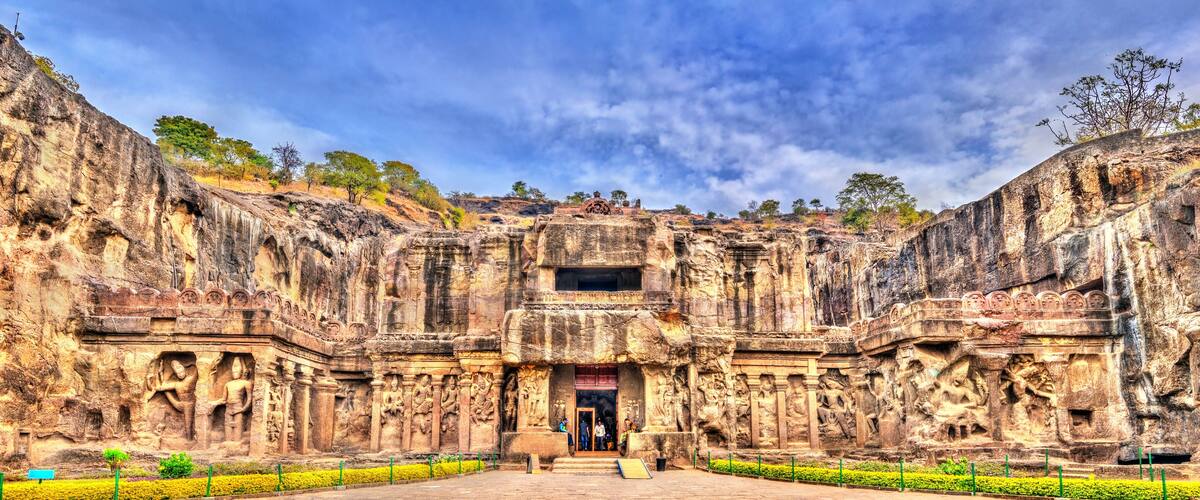 A large, ancient rock-cut temple with intricate carvings and a central doorway.