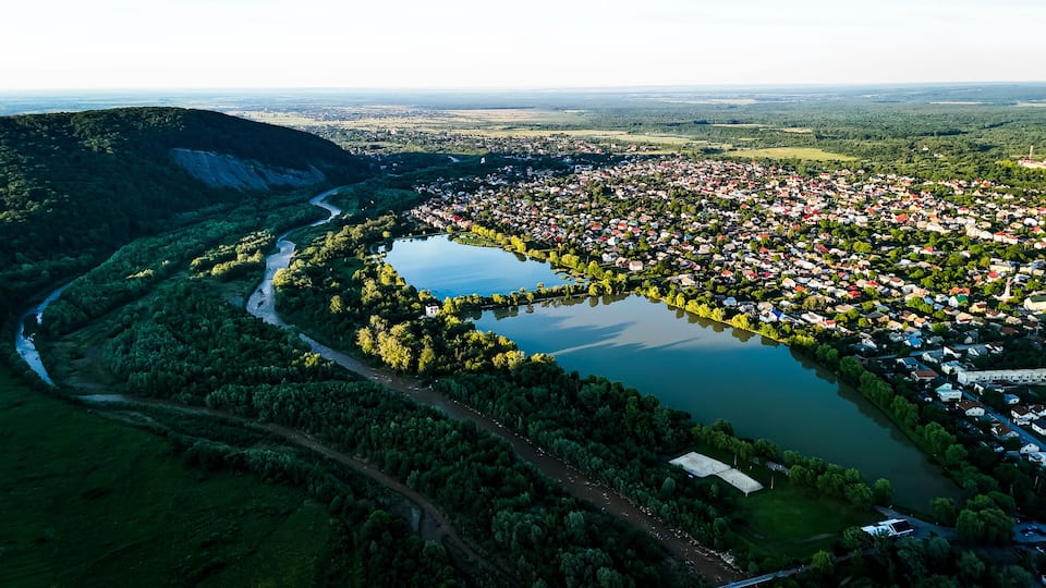 Twin lakes mirror the sky next to a compact town bordered by sweeping woodland