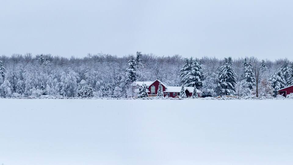 A snowy landscape with a red barn and a red shed.