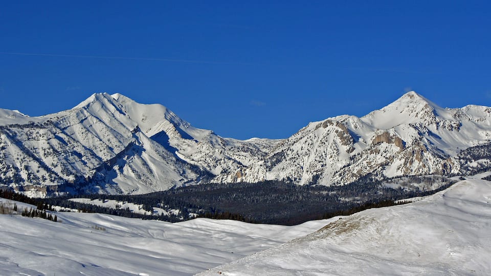 A snow-covered mountain range with clear blue skies.