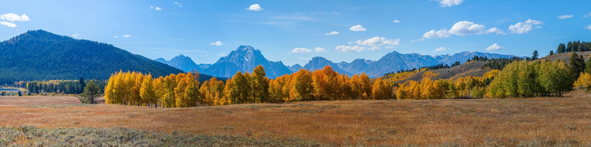 A mountainous landscape with autumn-colored trees and a clear blue sky.