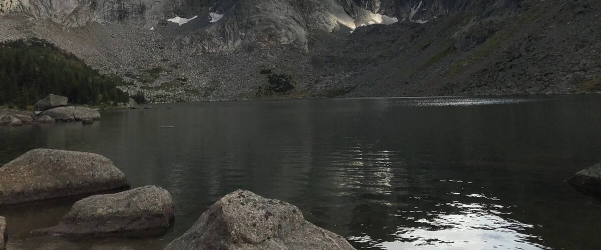 A mountain range with a lake in the foreground.