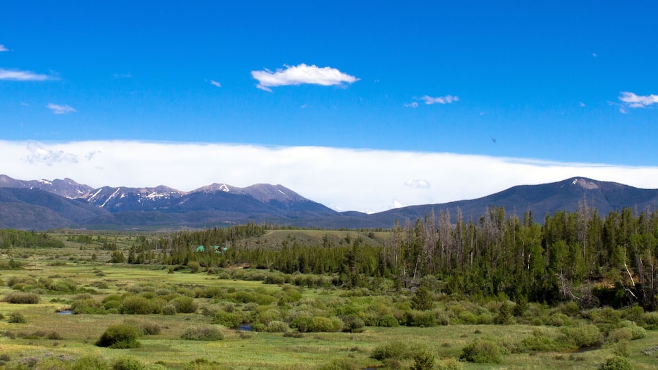 A mountainous landscape with a clear sky, a river, and a forested area.