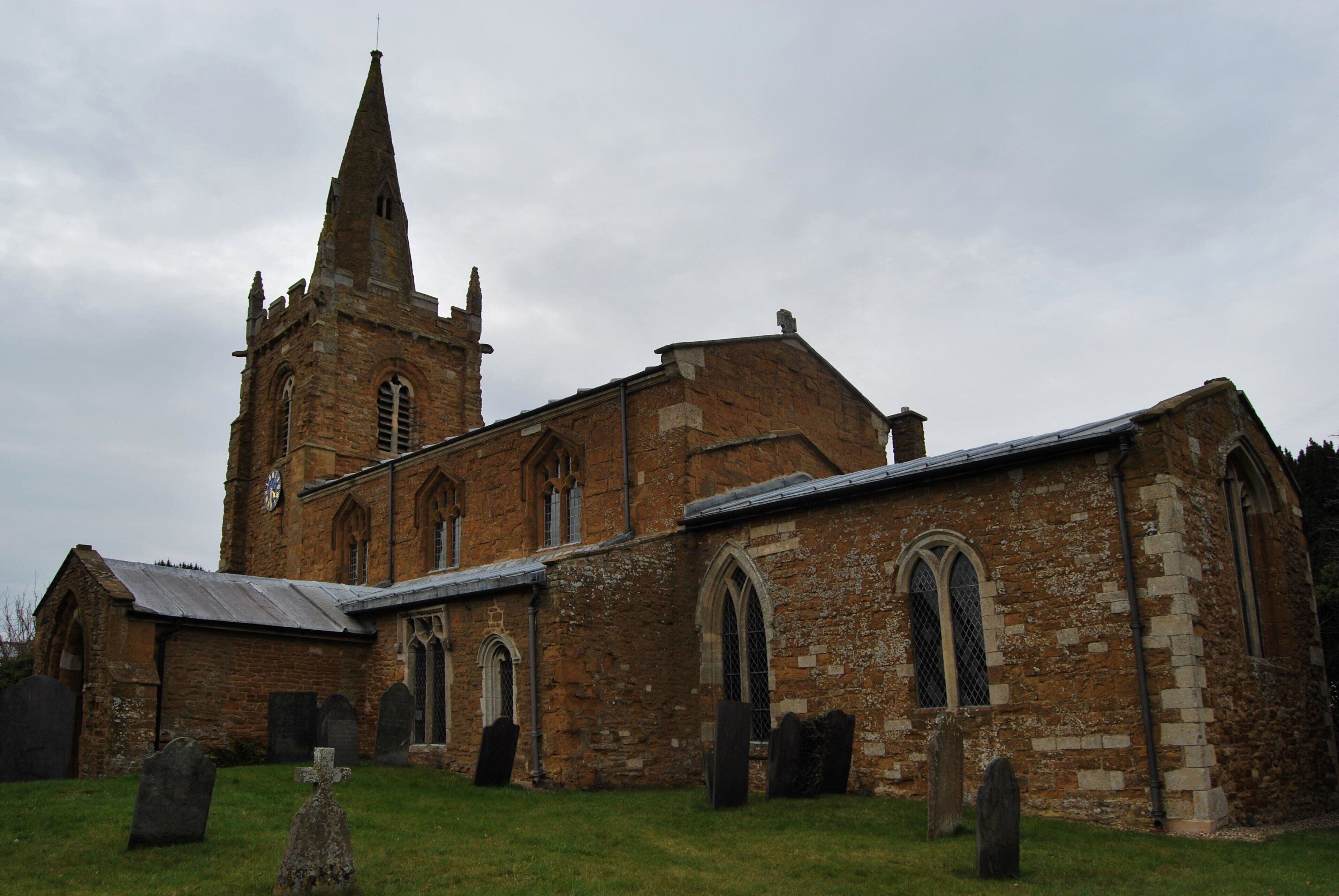 An old church with a tall spire and multiple arched windows.