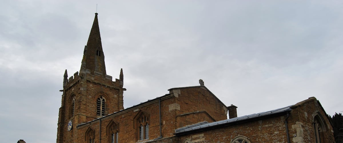 An old church with a tall spire and multiple arched windows.