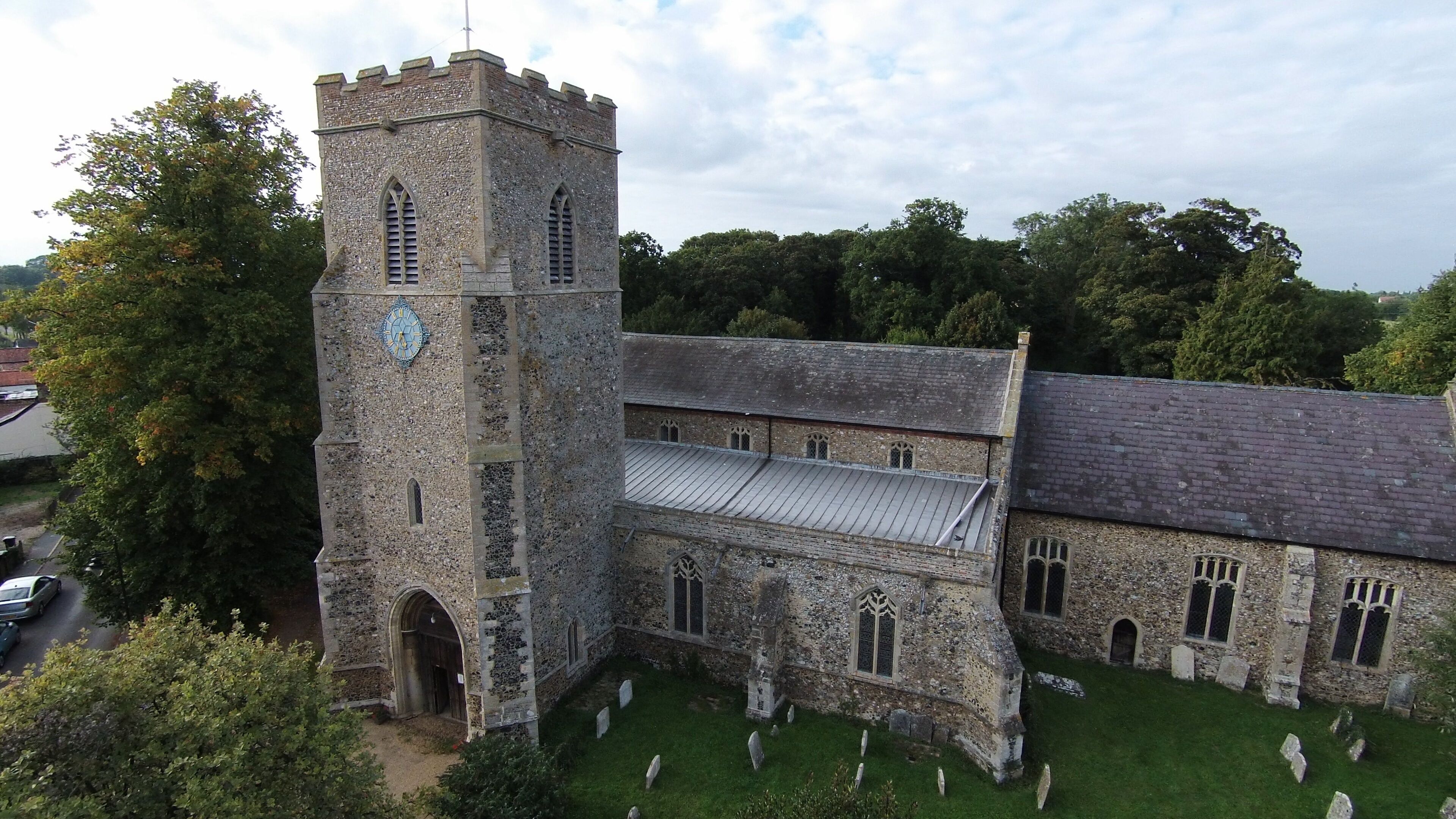 A historic stone church with a clock tower, surrounded by a cemetery.
