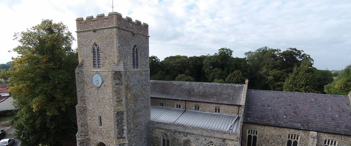 A historic stone church with a clock tower, surrounded by a cemetery.