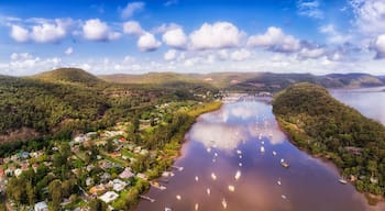 Une rivière où naviguent des bateaux, bordée de collines boisées et surplombée d’un ciel dégagé.