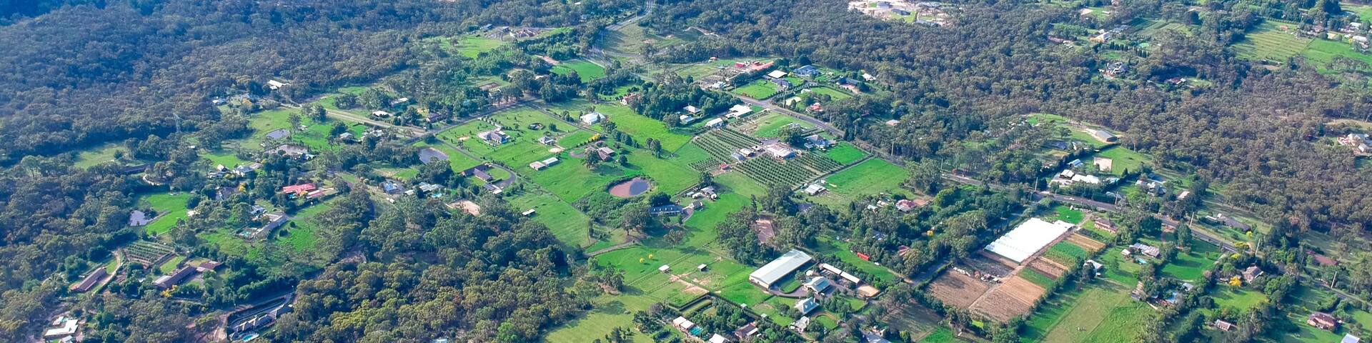 An aerial view of a rural landscape with fields, scattered buildings, and dense forest areas.