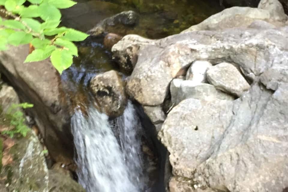 Uma pequena cascata corrente sobre rochas em um riacho pedregoso.