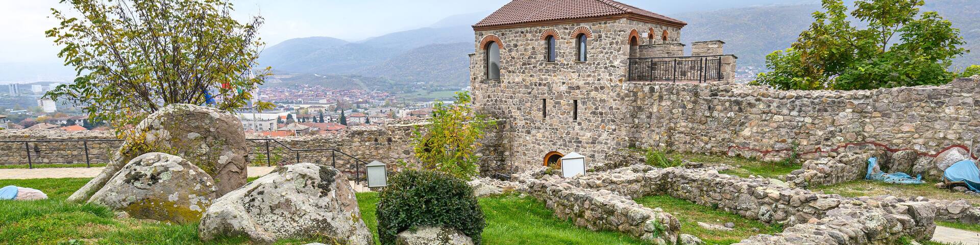 A stone building with a tiled roof surrounded by grass and rocks.
