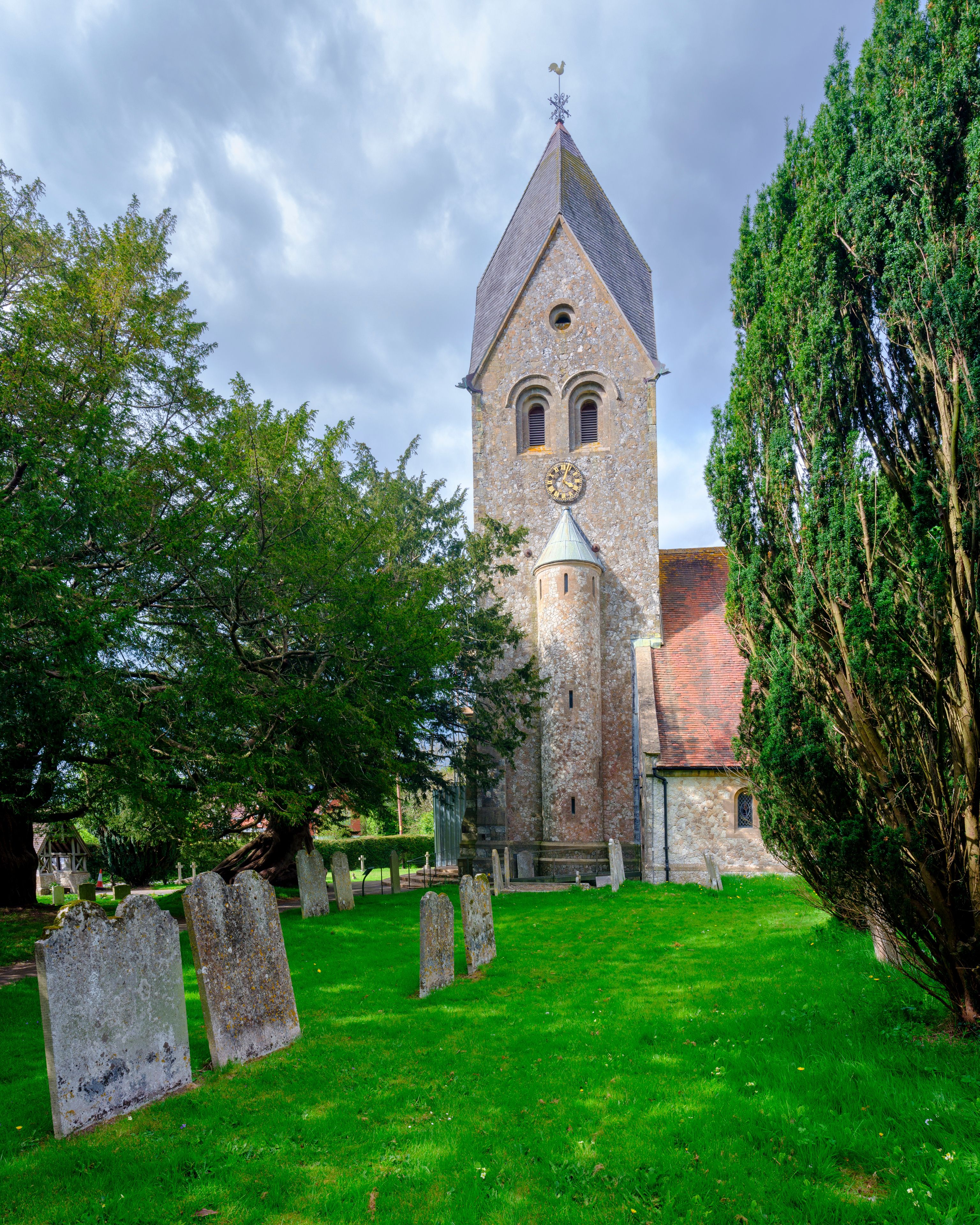 Una chiesa con un campanile alto, circondata da un cimitero con lapidi.