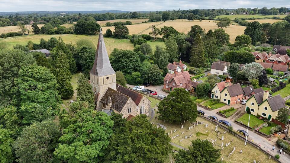 An aerial view of a village with a church, houses, and a cemetery.