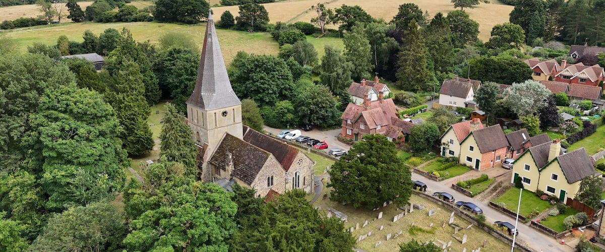 An aerial view of a village with a church, houses, and a cemetery.
