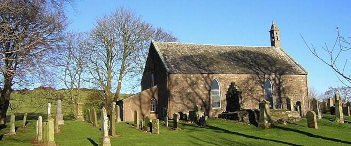 A church with a bell tower, surrounded by a cemetery with gravestones.