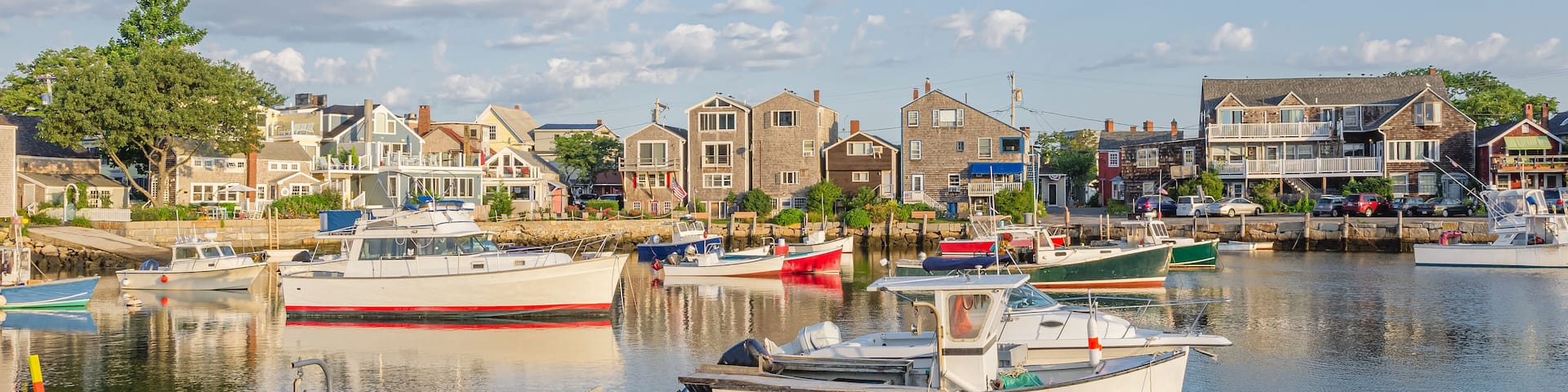 A harbor with several boats docked, surrounded by houses and a clear sky.