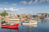 A harbor with several boats docked, surrounded by houses and a clear sky.