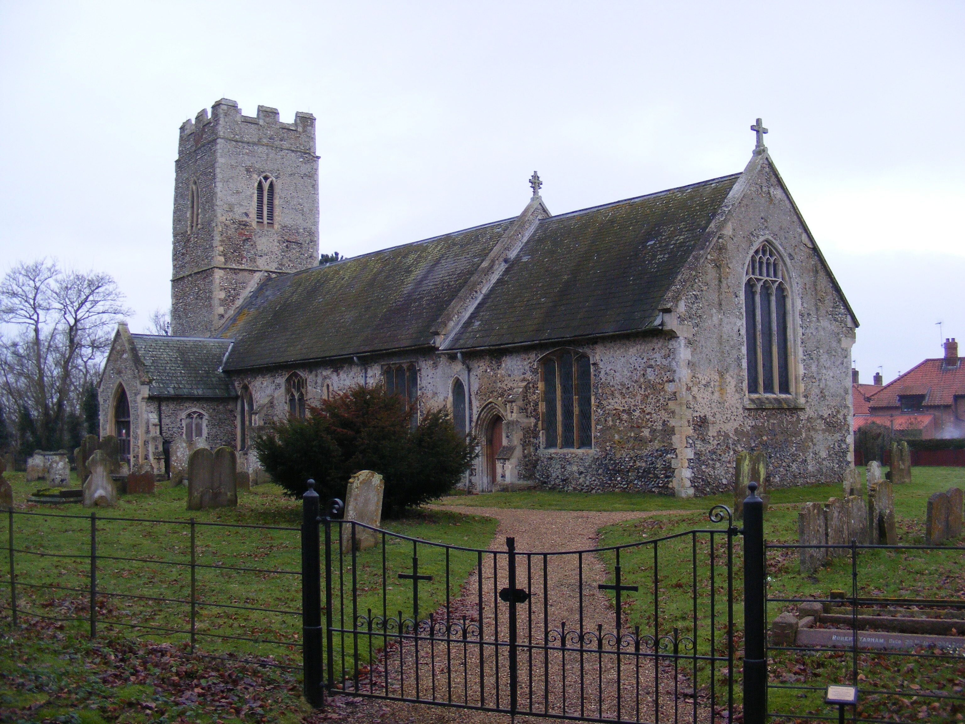 A historic church with a tall tower and a smaller steeple, surrounded by a cemetery with headstones.