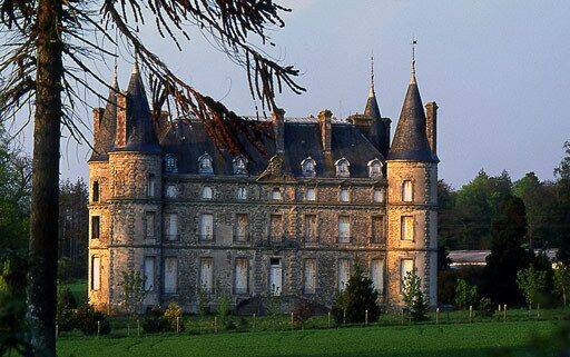 A large stone castle with multiple towers and a well-maintained lawn.