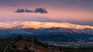 Una cordillera nevada al atardecer con un pueblo en el valle.