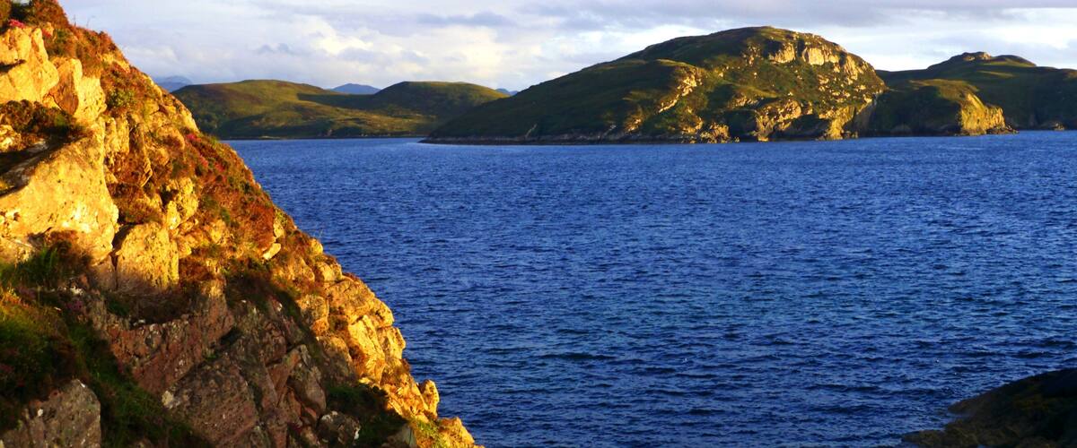 A coastal landscape with rocky cliffs and calm sea.