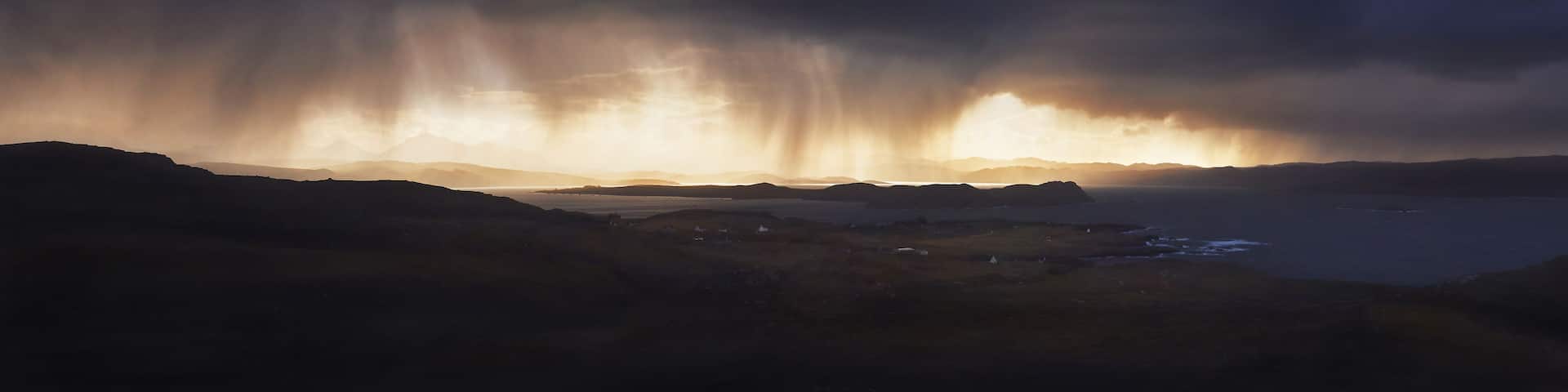 A stormy landscape with a dramatic sky and a body of water in the foreground.