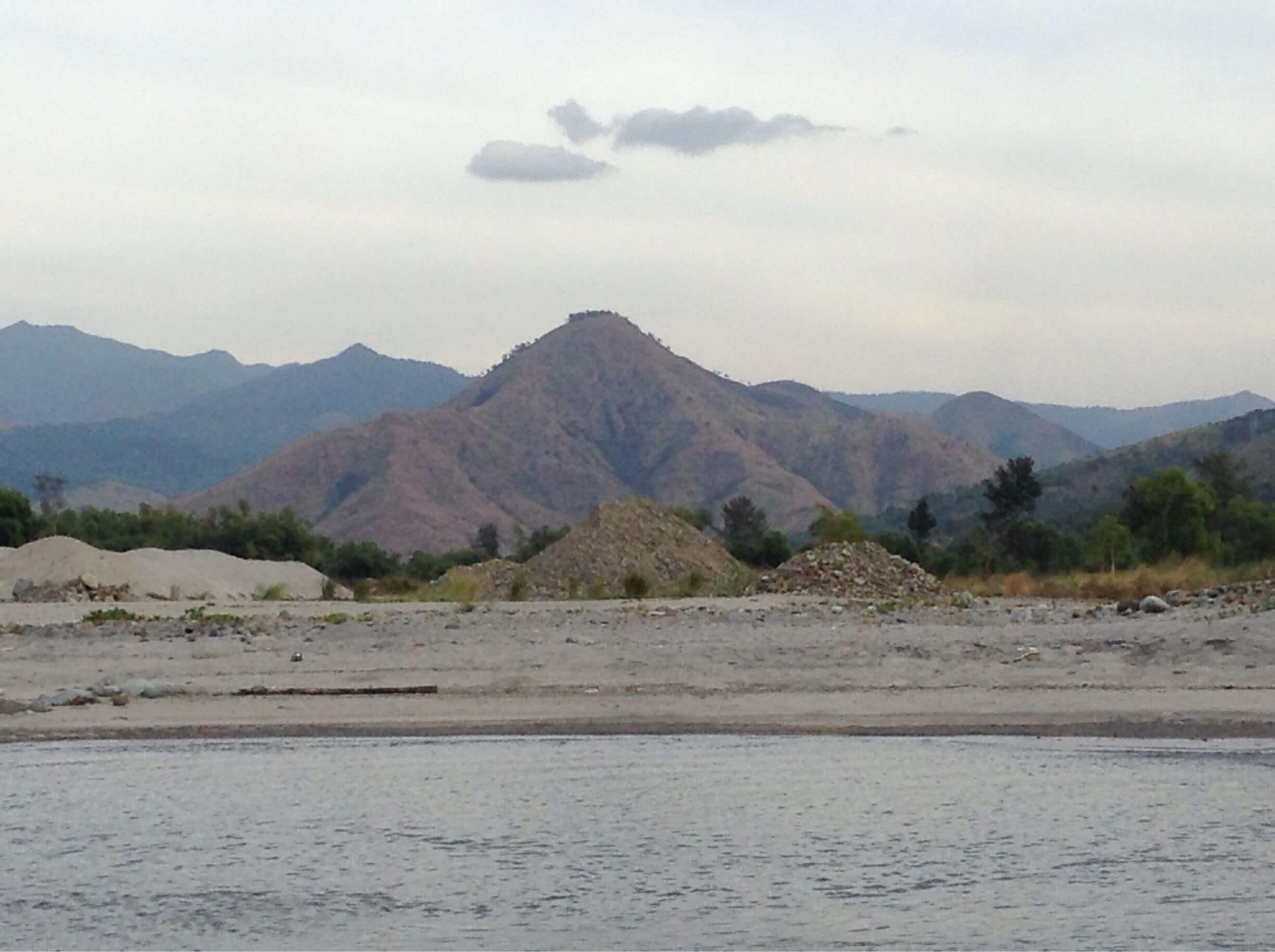 A mountainous landscape with a prominent peak and piles of construction materials in the foreground.
