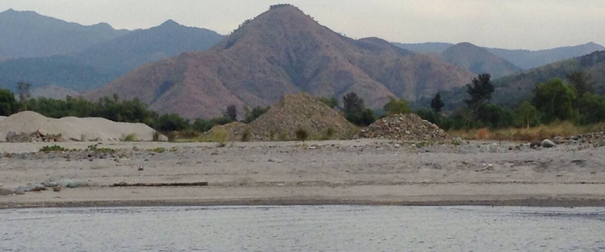 A mountainous landscape with a prominent peak and piles of construction materials in the foreground.