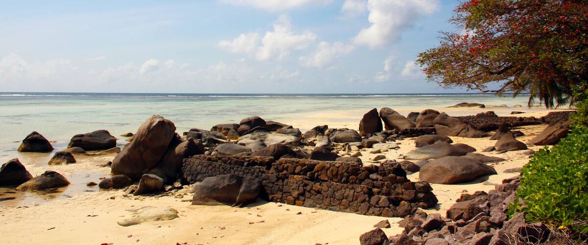 A rocky beach with large boulders and a clear blue sky.