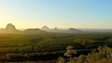 A forested landscape with prominent mountain peaks during sunrise.