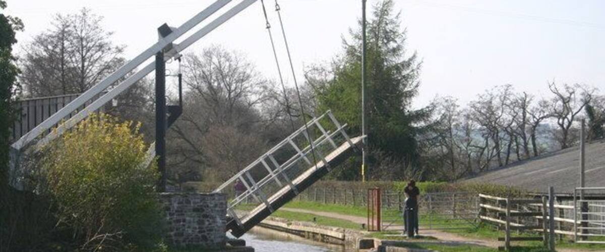 A canal with a drawbridge and a person standing on the bridge.