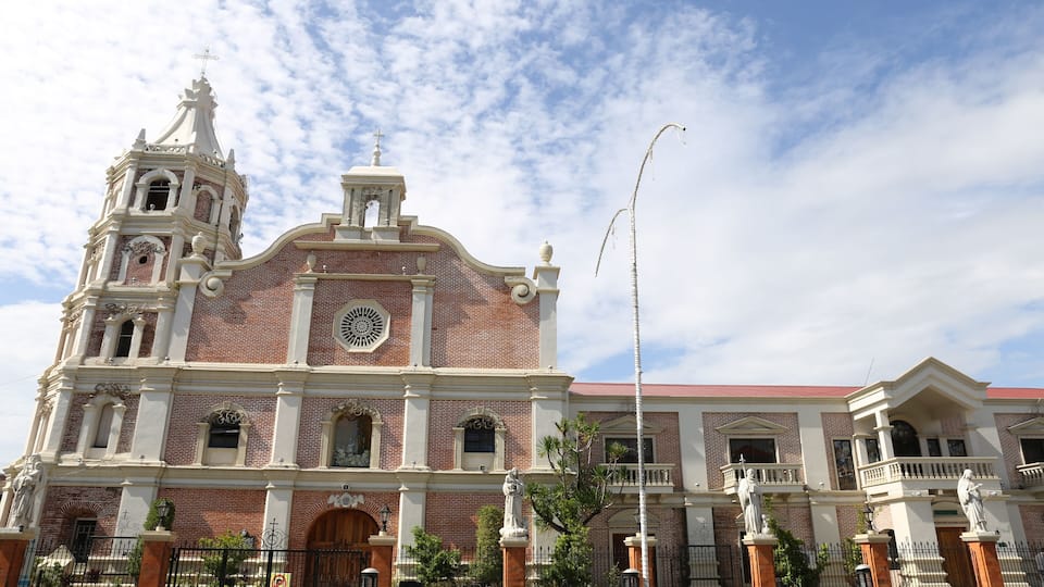 A large, historic church with a bell tower and statues in front.