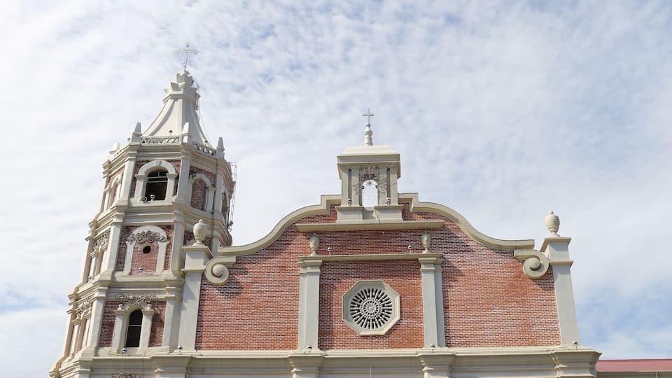 A large brick church with a bell tower and a clock.