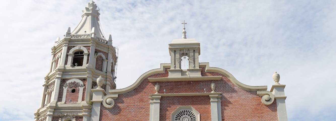 Una iglesia de ladrillo grande con un campanario y un reloj.