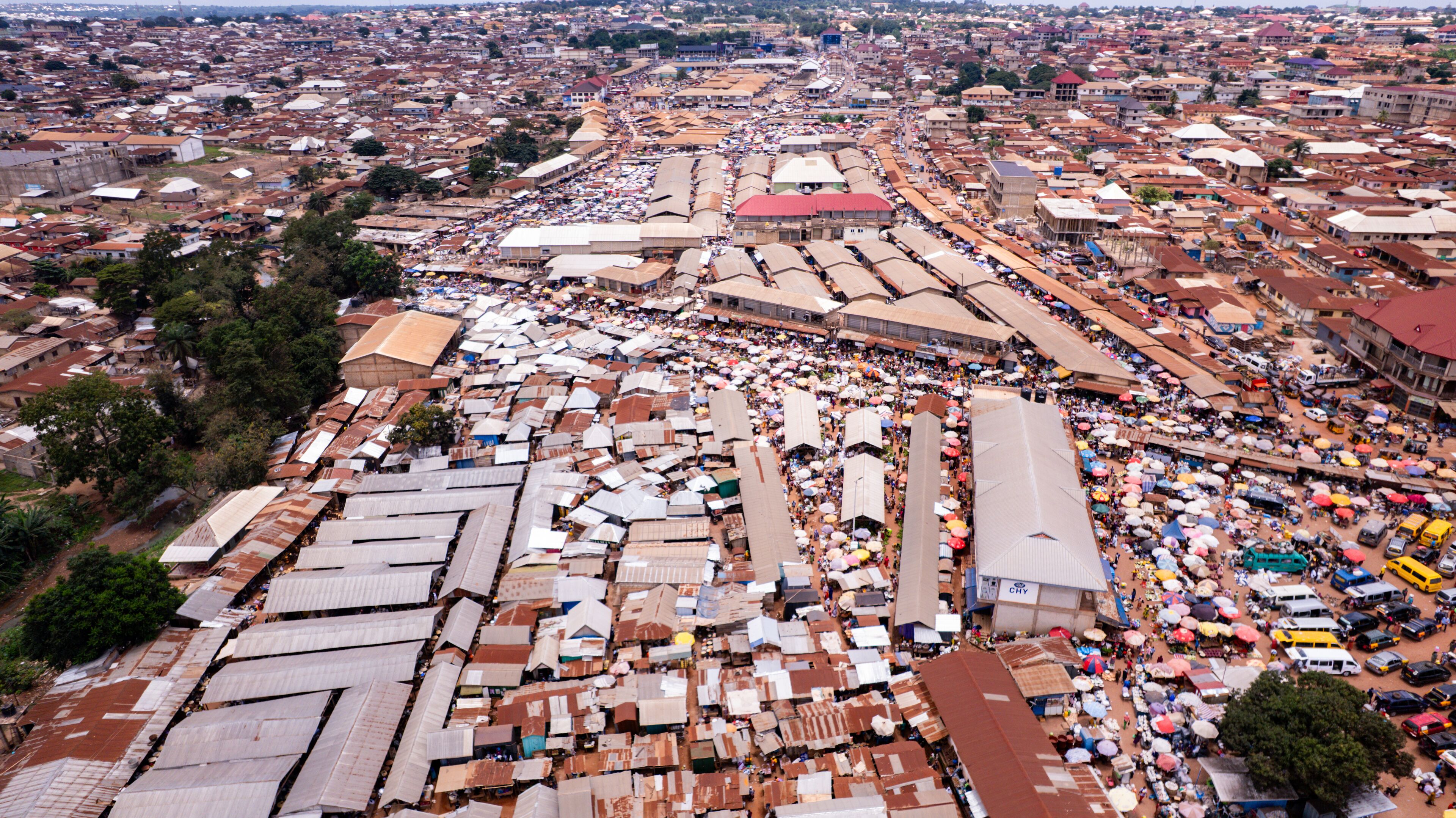 A densely packed urban market with numerous makeshift stalls and a large crowd.