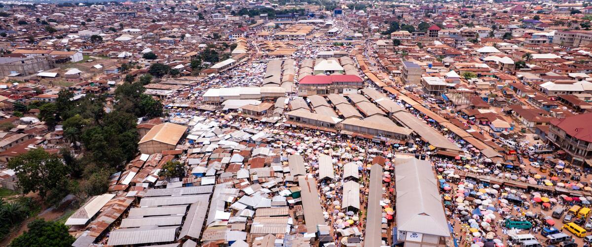 A densely packed urban market with numerous makeshift stalls and a large crowd.