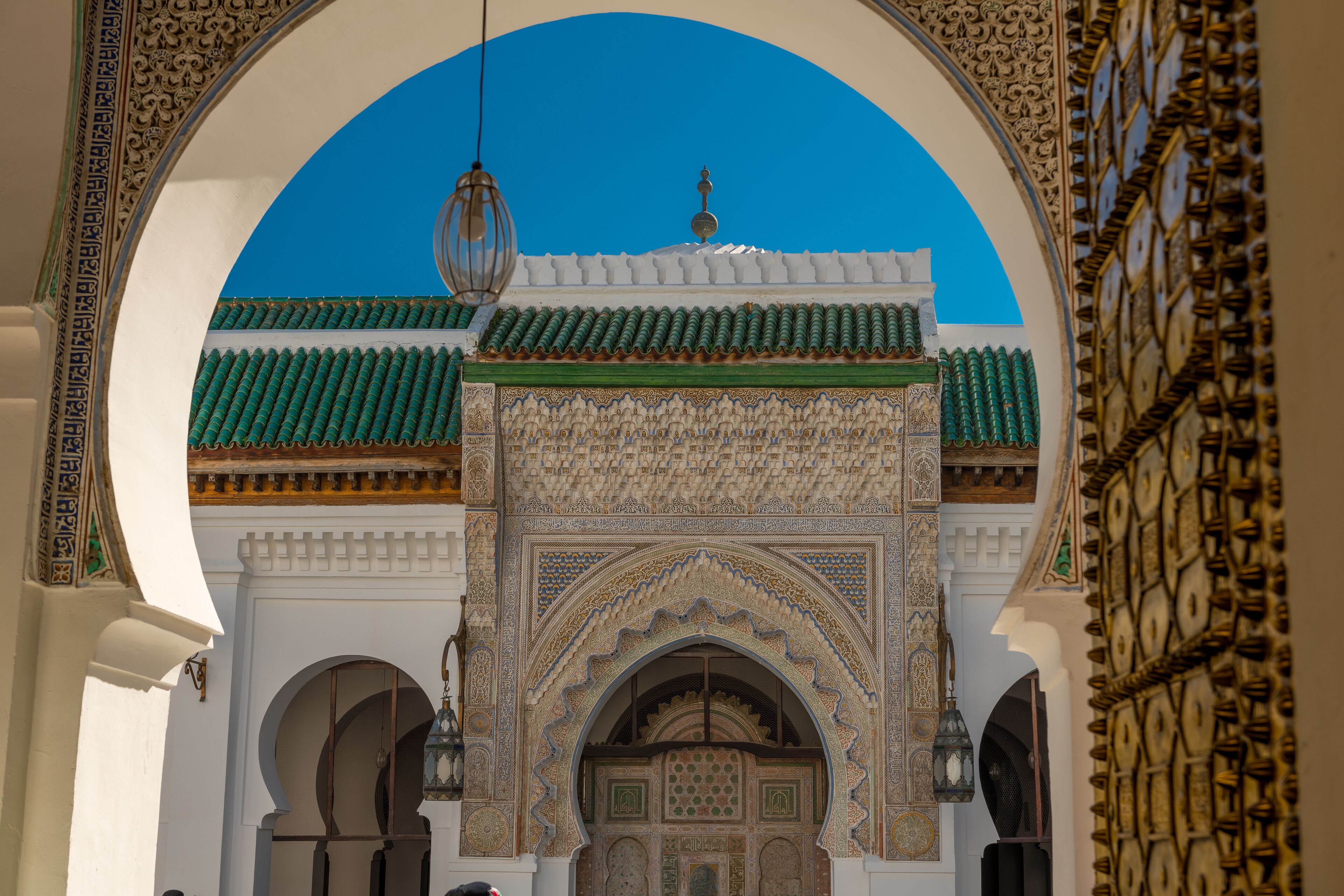 A detailed view of a traditional archway with intricate tile work and a hanging lantern.