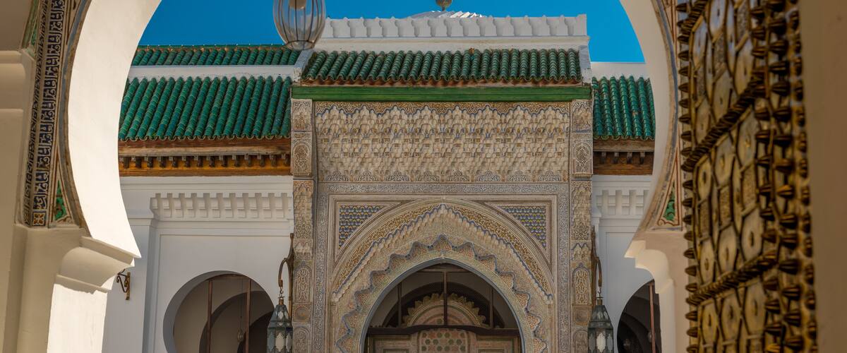 A detailed view of a traditional archway with intricate tile work and a hanging lantern.