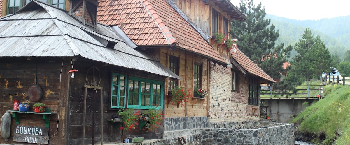 A wooden house with a stone foundation and a red-tiled roof.