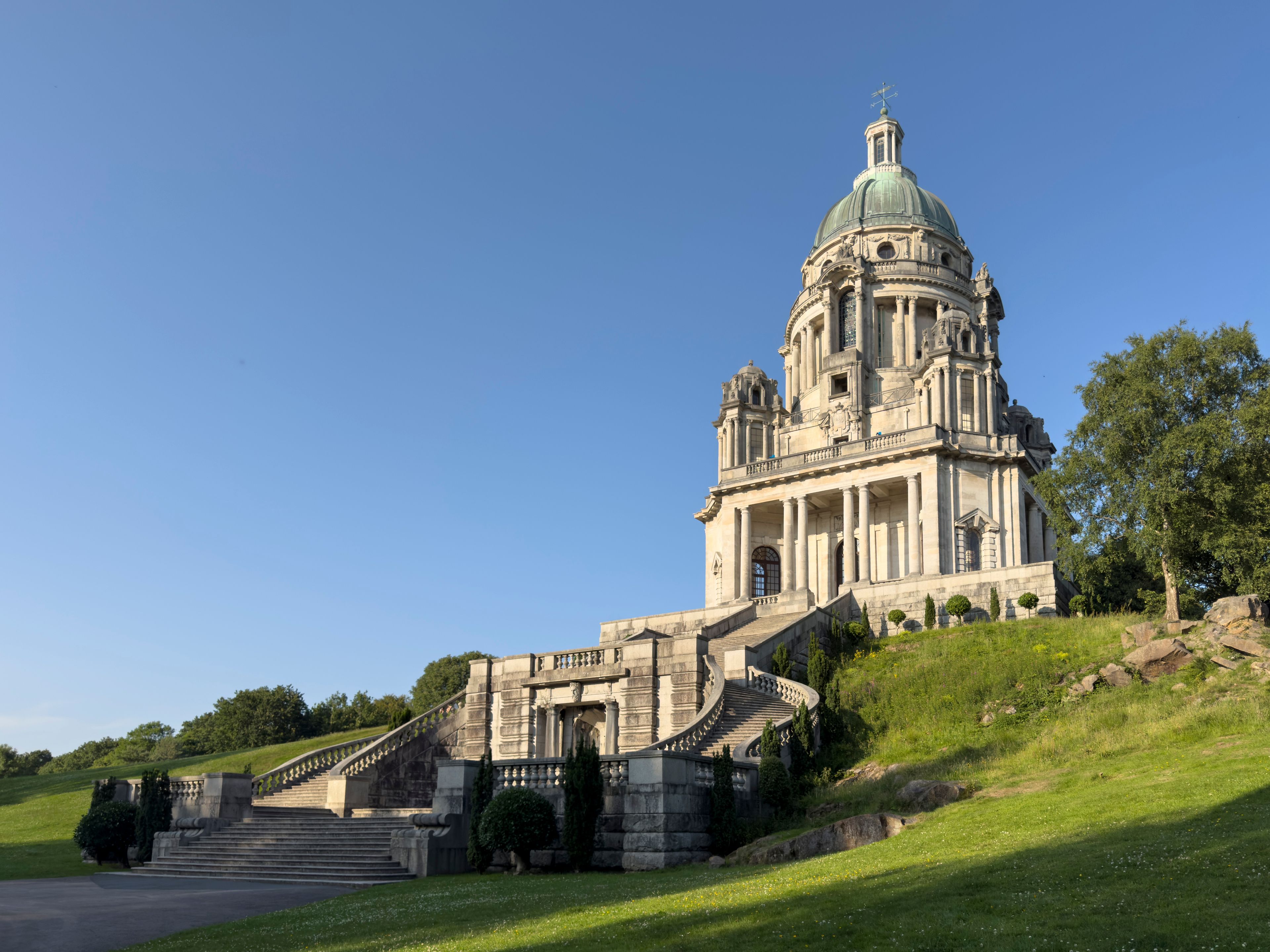 A grand neoclassical building with a dome and a staircase leading up to its entrance.