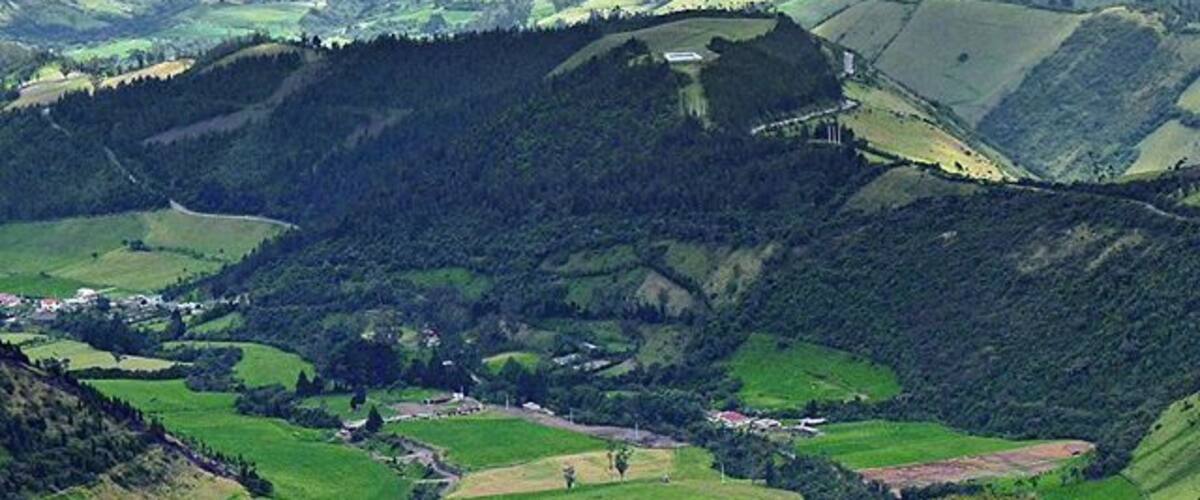 A valley with rolling hills, a river, and scattered buildings.