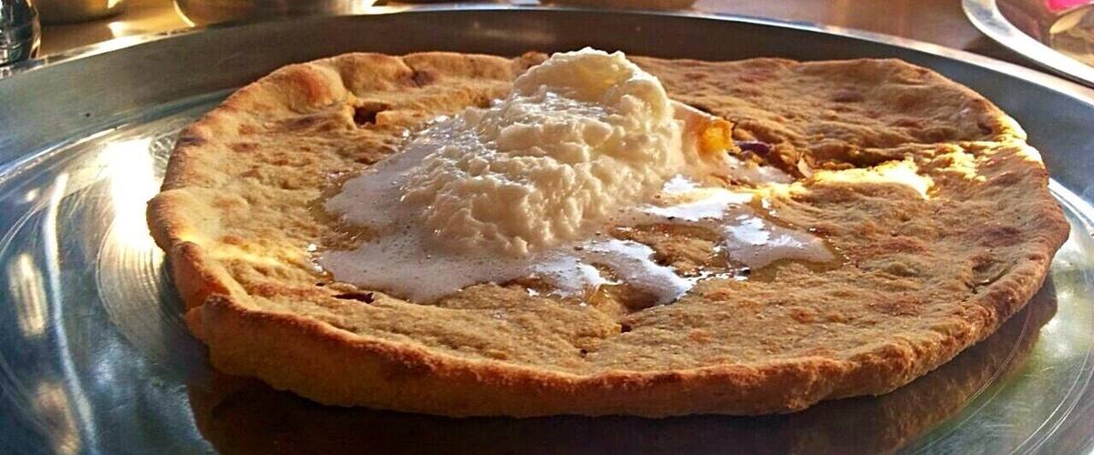 A flatbread with a dollop of white sauce on a metal plate.