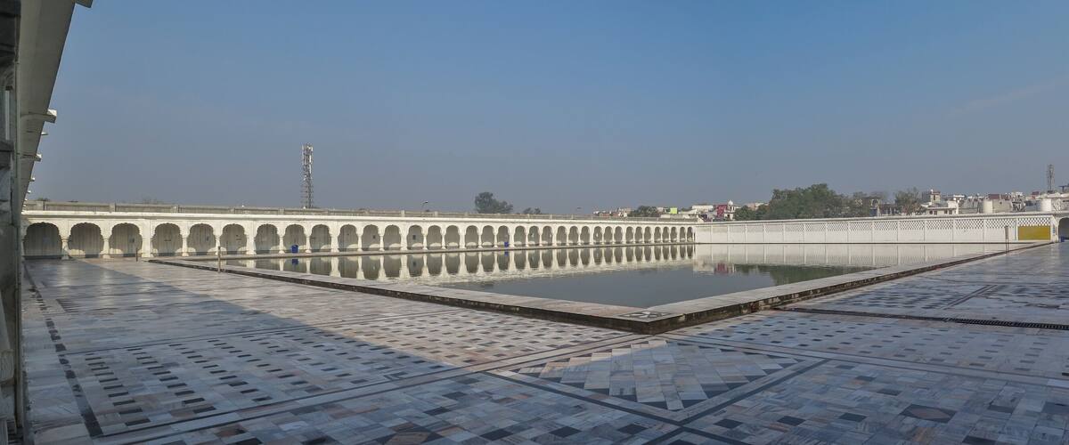 A courtyard with a reflective pool, ornate arches, and a tiled floor.