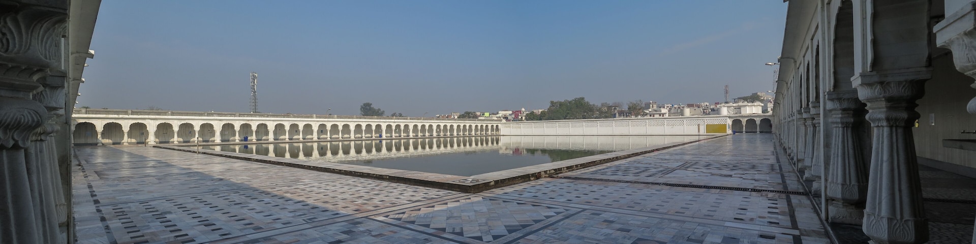 A courtyard with a reflective pool, ornate arches, and a tiled floor.