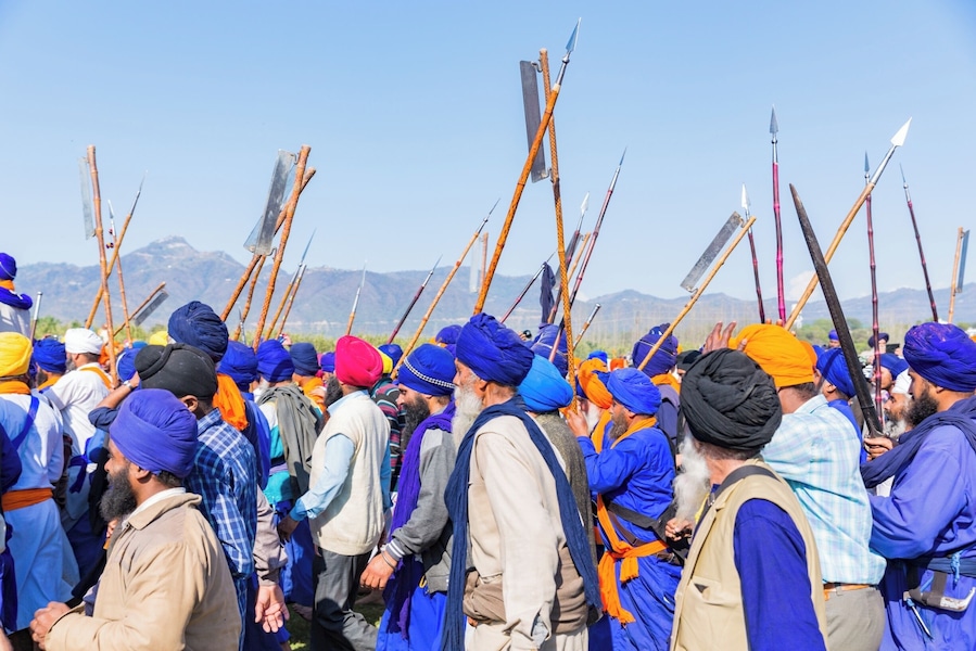 #Blue. This image is from Hola Mohalla, a tradition of annual celebration of valour started by Sikh Guru, Guru Gobind Singh. This celebration happens in Anandpur Sahib, a small town in the northern Indian state of Punjab. The procession of sharp-edged weapon wielding Nihang Sikhs is completely peaceful. The show-stopper of this festivity is show riding - daredevil riders ride 3 or even 4 galloping horses standing upright holding the reigns in their mouth.