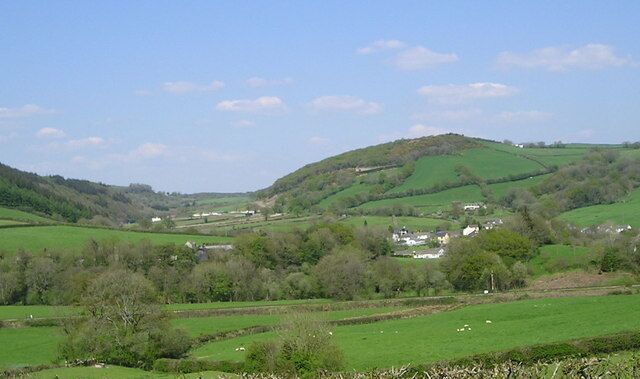 Rural Scene at Bronwydd This view from the A484 shows part of the village of Bronwydd among scattered woods and green fields. In the valley of the Nant Brechfa, beyond left, you can just see the circuit for training horses kept at the stables behind the large house called Felinfach.