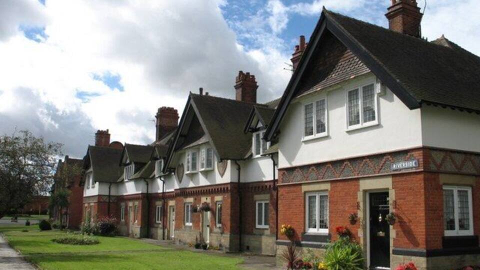 A row of traditional brick houses with white trim and green lawns.