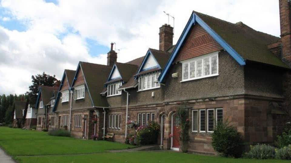A row of brick houses with pitched roofs and blue trim.