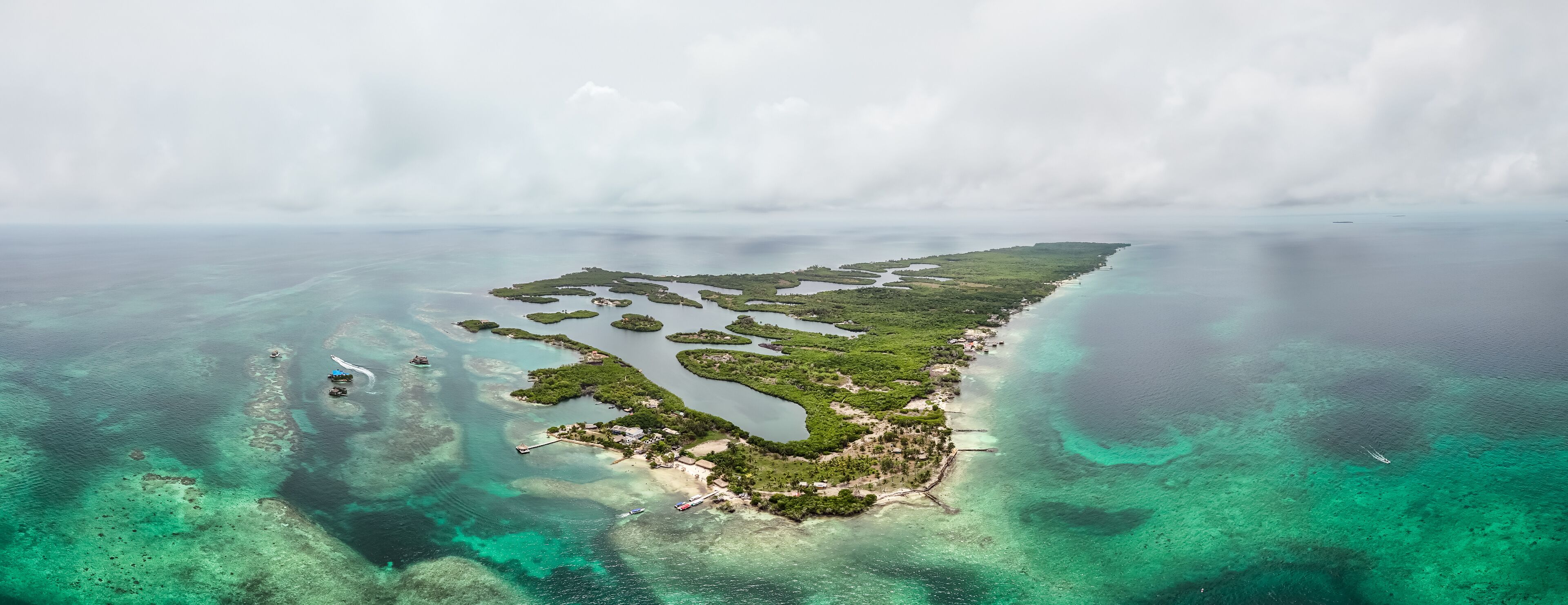An aerial view of a coastal island with clear turquoise waters, green vegetation, and small inlets.