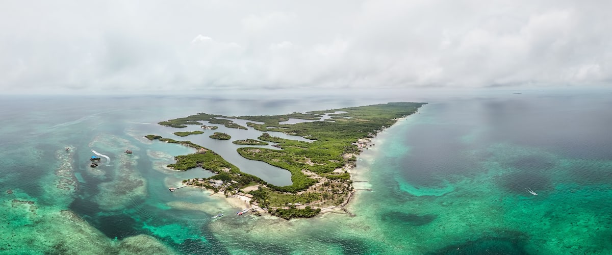 An aerial view of a coastal island with clear turquoise waters, green vegetation, and small inlets.